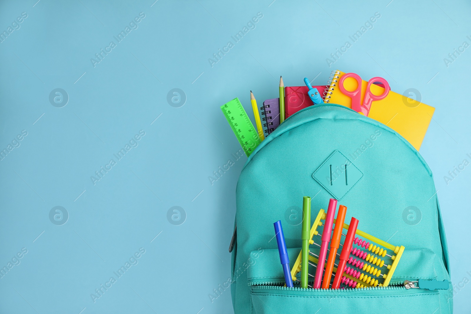 Photo of Stylish backpack with different school stationary on light blue background, top view. Space for text