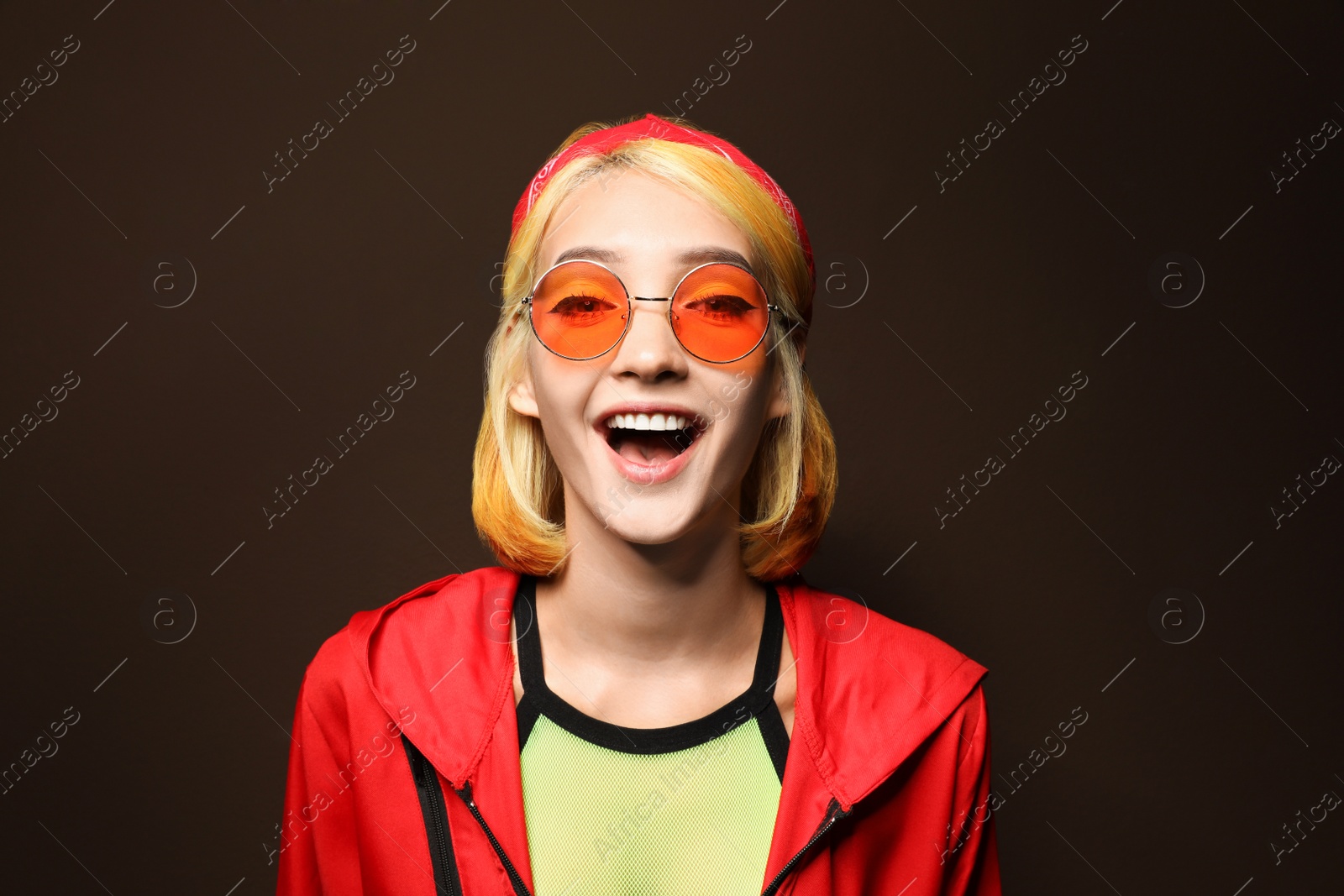 Photo of Beautiful young woman with bright dyed hair on brown background