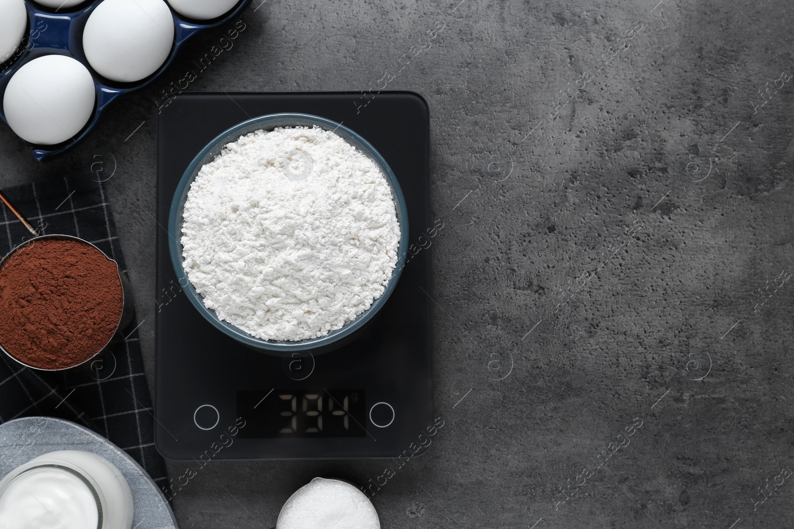 Photo of Electronic scales with flour and different products on grey table, flat lay. Space for text