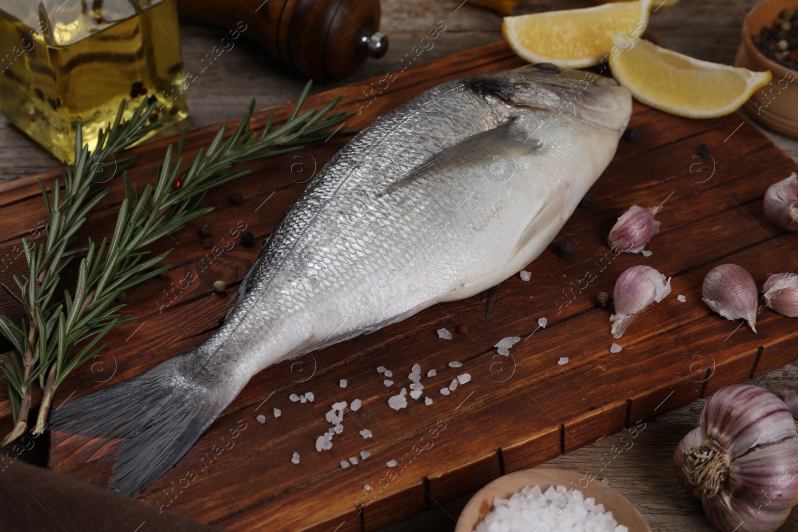 Photo of Raw dorado fish, lemon wedges and spices on wooden table