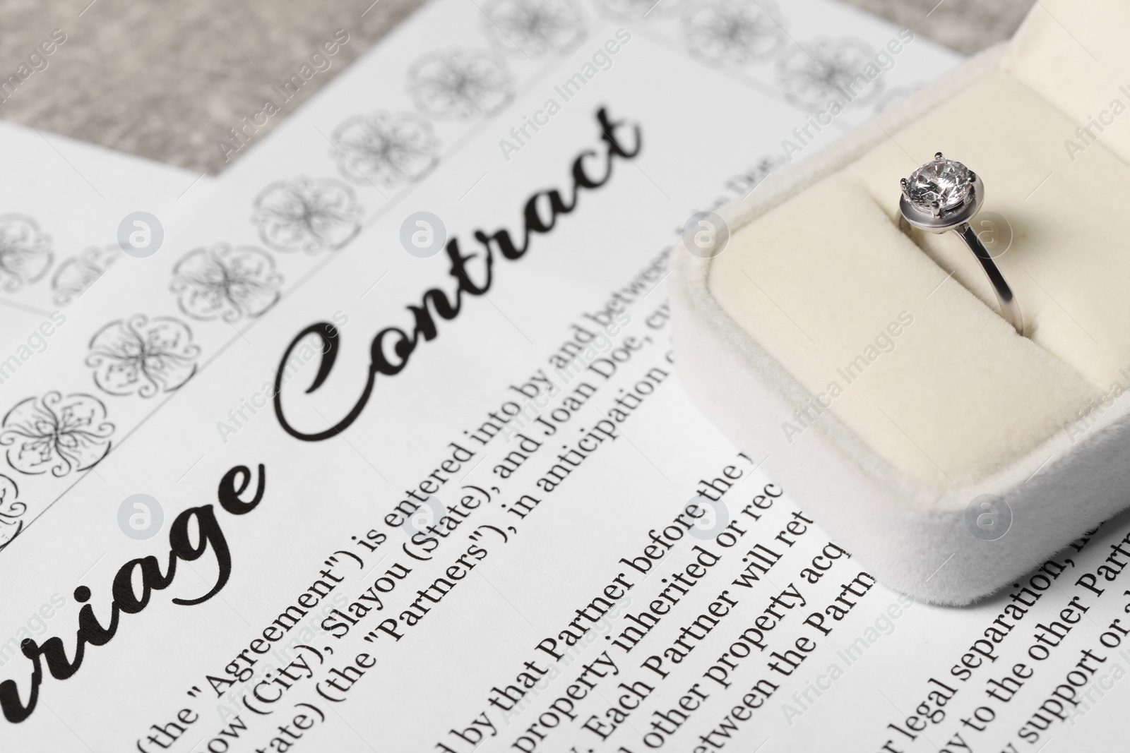 Photo of Marriage contract and ring with gemstone on table, closeup