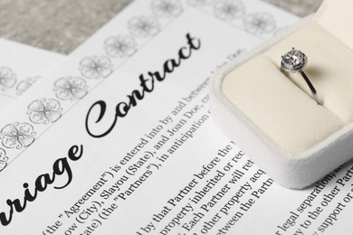 Marriage contract and ring with gemstone on table, closeup
