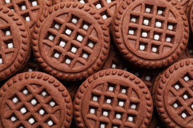 Tasty chocolate sandwich cookies with cream as background, top view