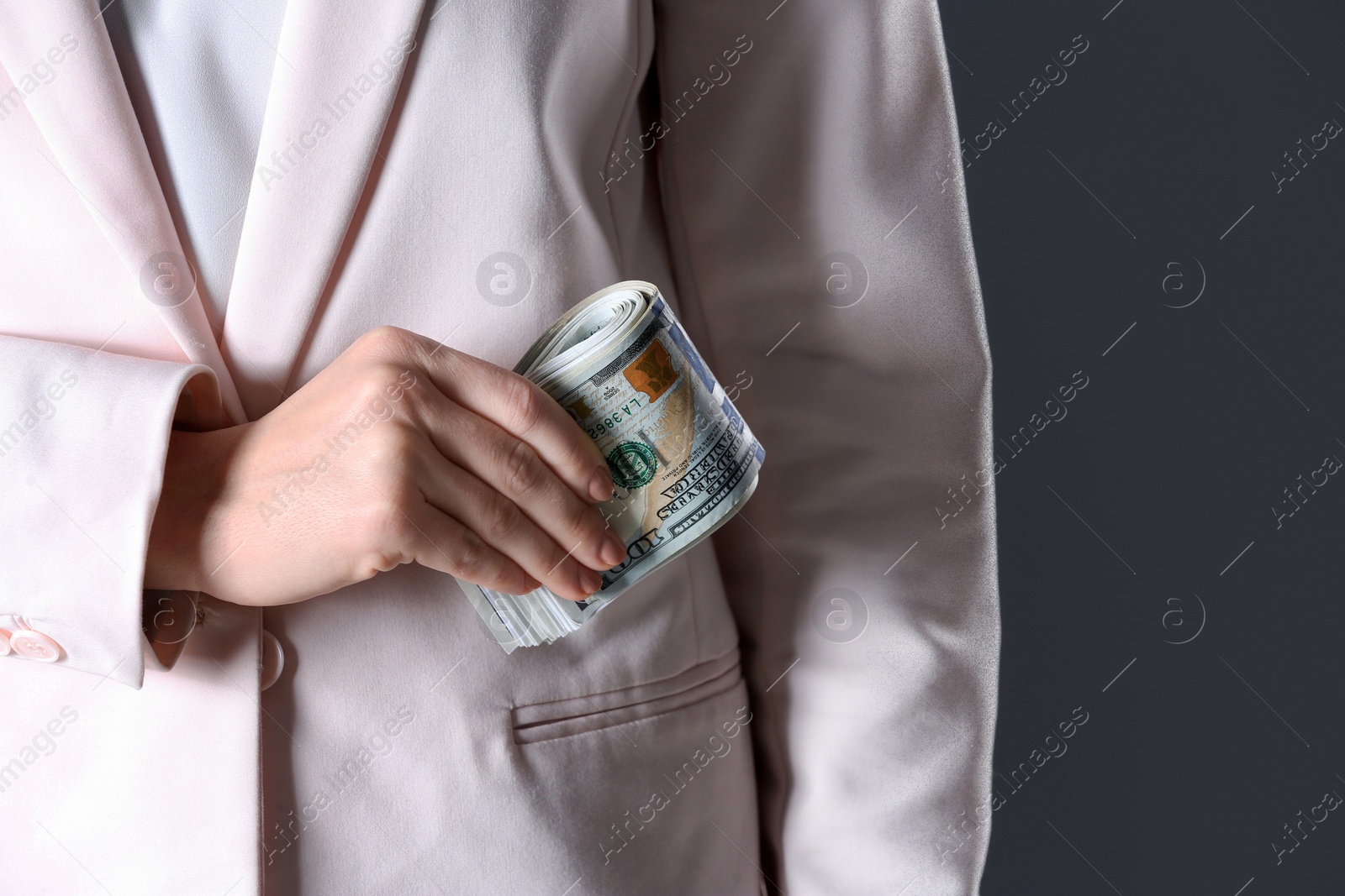 Photo of Woman putting bribe into pocket on black background, closeup