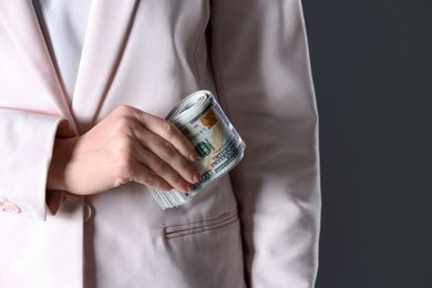 Photo of Woman putting bribe into pocket on black background, closeup