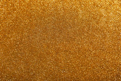 Photo of Shiny bright golden glitter as background, top view