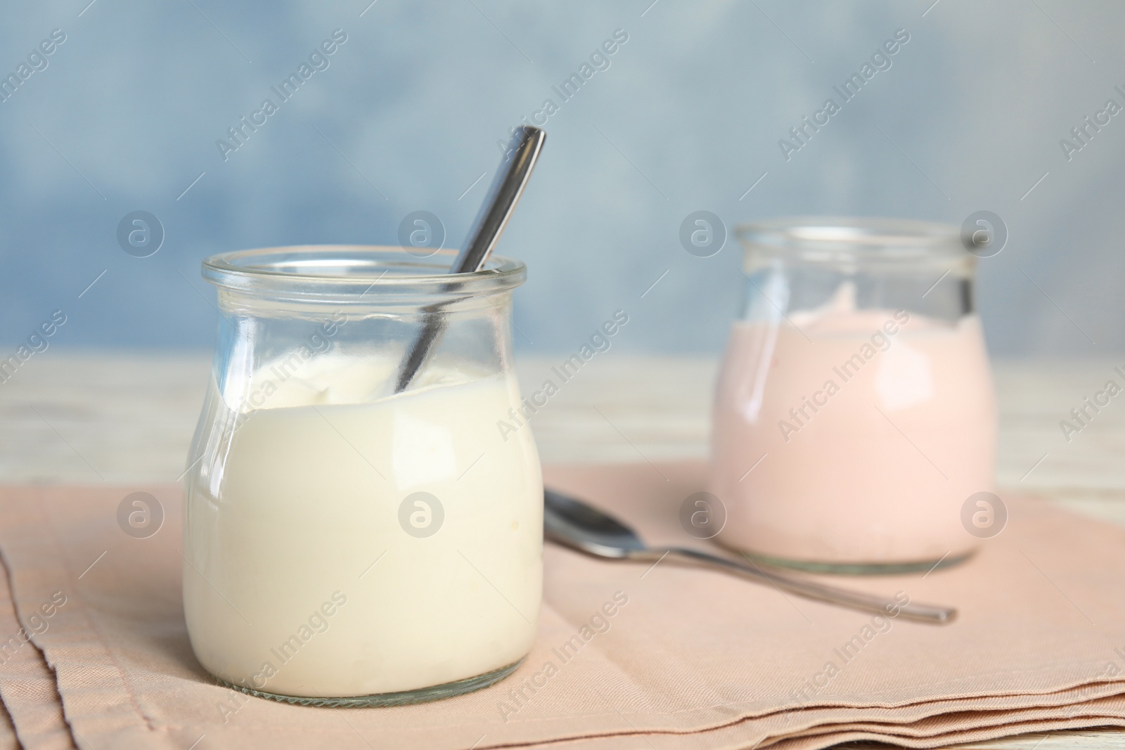 Photo of Tasty organic yogurt on fabric against light blue background. Space for text