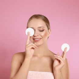 Photo of Beautiful young woman with cotton pads on pink background