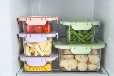 Containers with different frozen vegetables in refrigerator