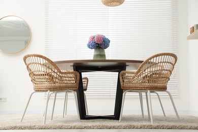 Photo of Table, chairs and vase of hydrangea flowers in dining room, low angle view. Stylish interior