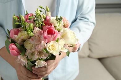 Photo of Man holding bouquet of beautiful flowers indoors, closeup