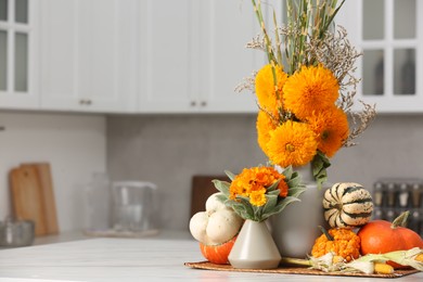 Beautiful autumn bouquets and pumpkins on marble table in kitchen