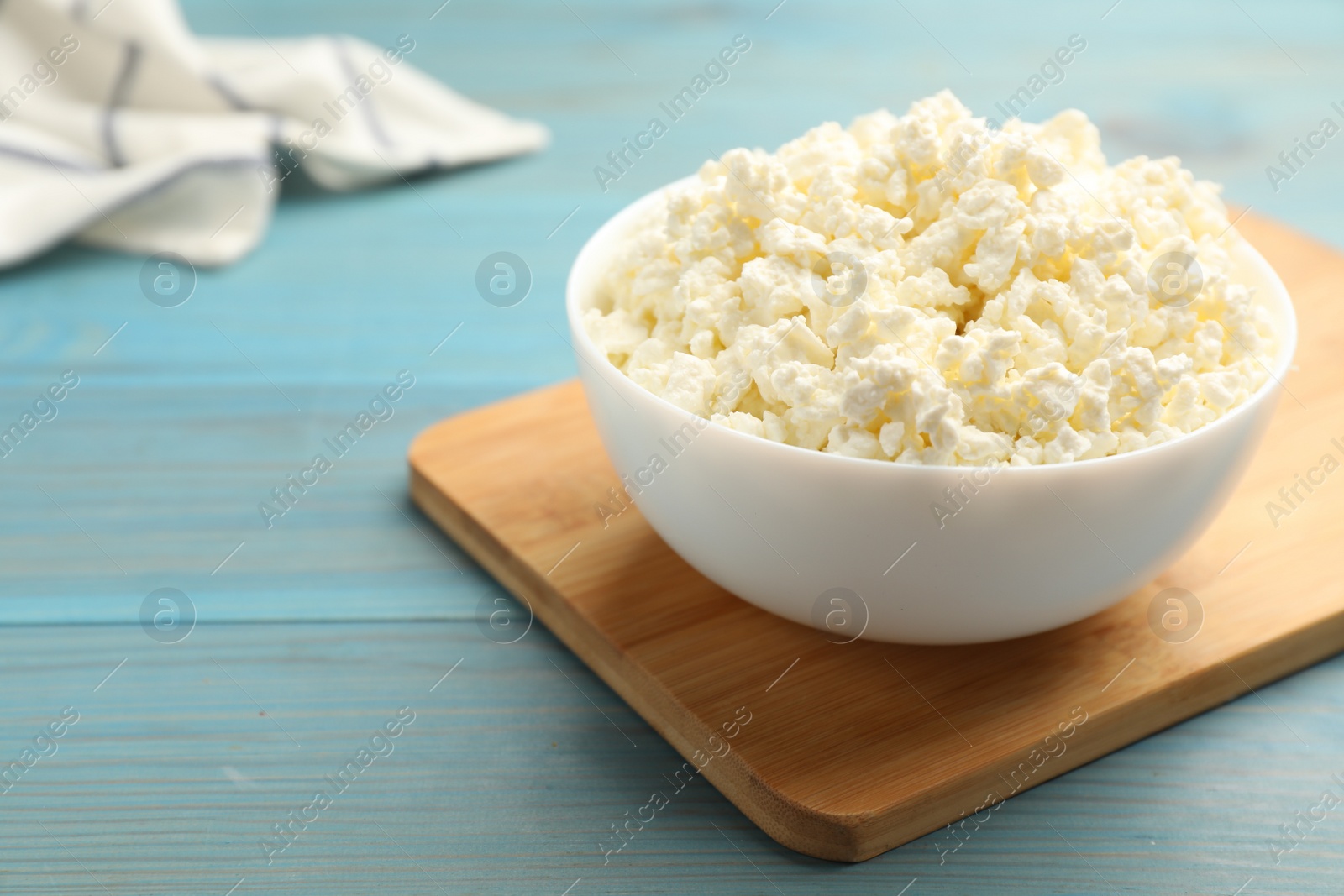 Photo of Delicious fresh cottage cheese on blue wooden table, closeup. Space for text