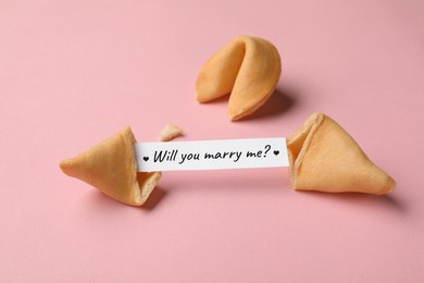 Image of Tasty fortune cookies and paper with phrase Will you marry me? on pink background