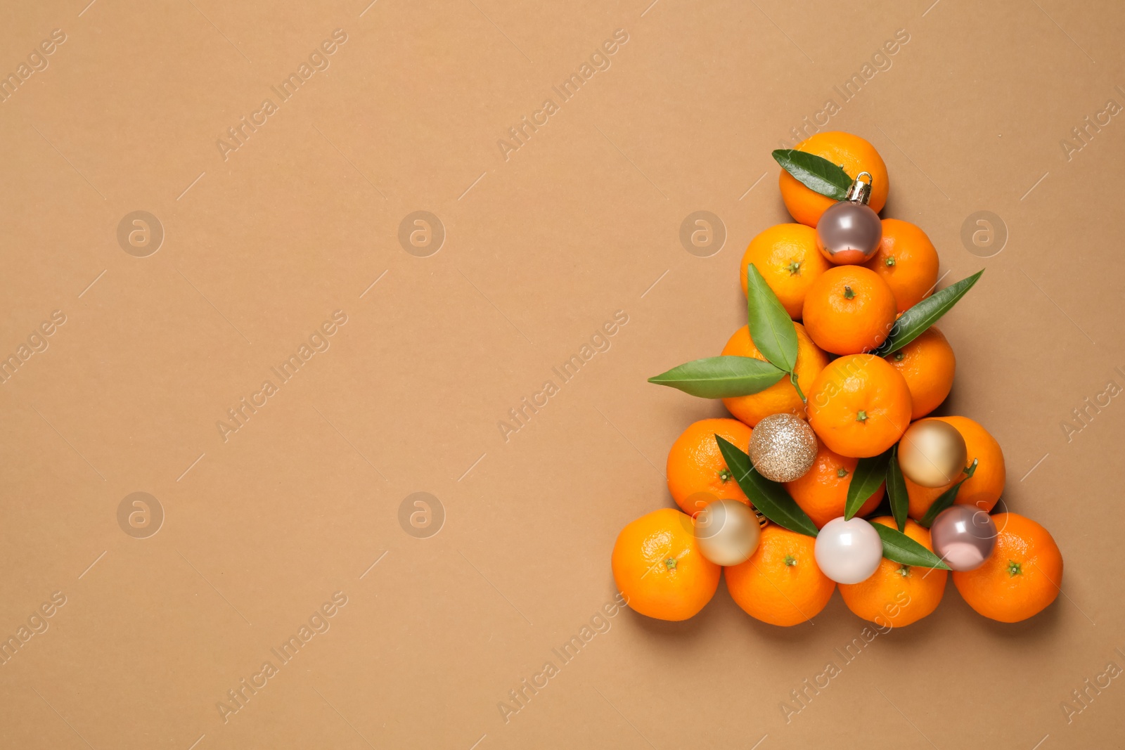 Photo of Christmas tree shape made of tangerines on light brown background, flat lay. Space for text