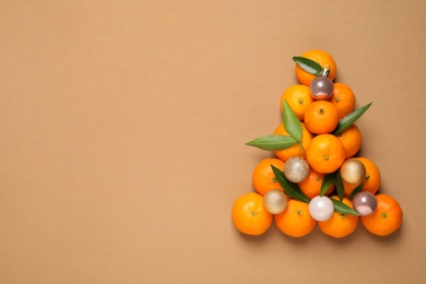 Christmas tree shape made of tangerines on light brown background, flat lay. Space for text
