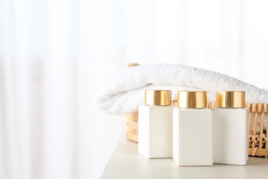 Photo of Cosmetic bottles and towel on light grey table indoors, space for text. Spa treatment