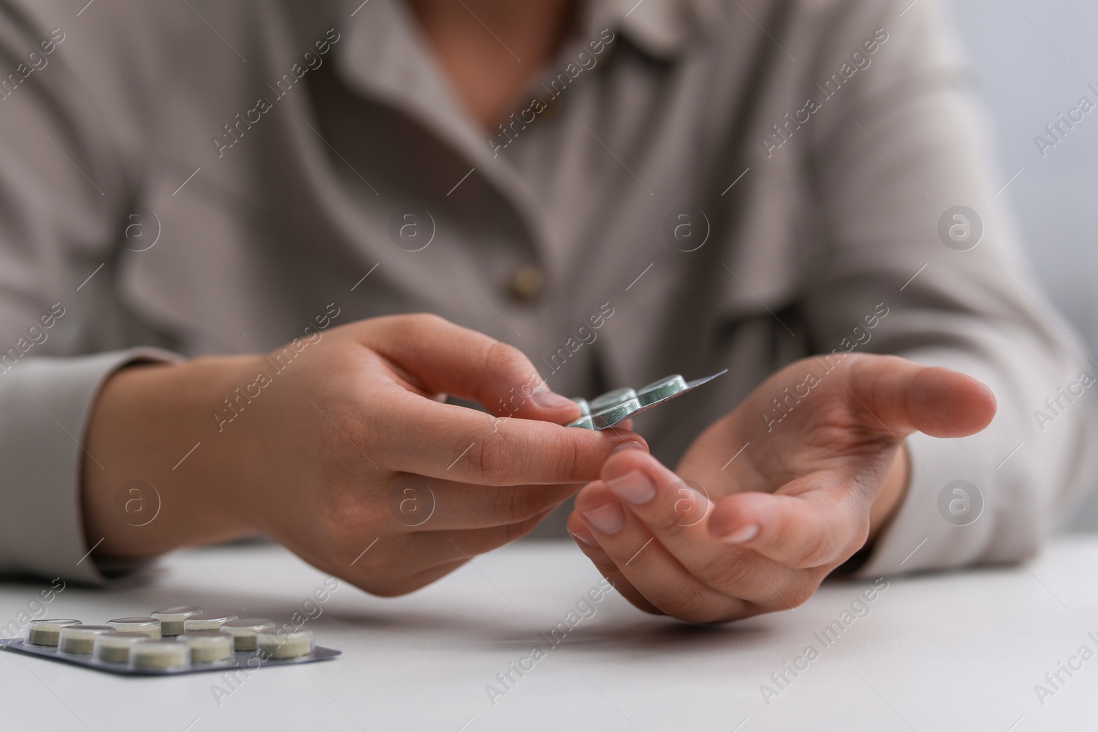 Photo of Woman taking antidepressant pill out from blister at white table, closeup