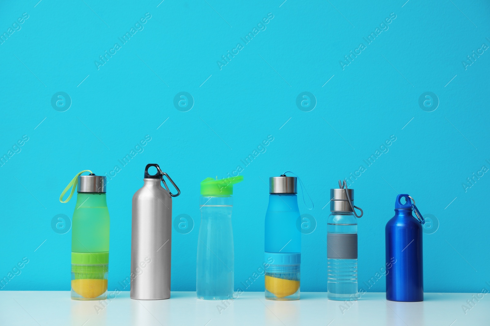 Photo of Different water bottles for sports on color background. Space for text