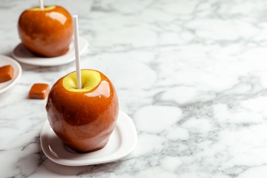 Photo of Delicious green caramel apple on marble table