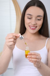 Photo of Young woman with essential oil in bathroom, selective focus