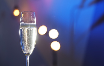 Photo of Glass of champagne on color background, closeup. Space for text