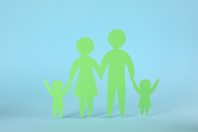 Photo of Paper family figure on light blue background. Child adoption concept