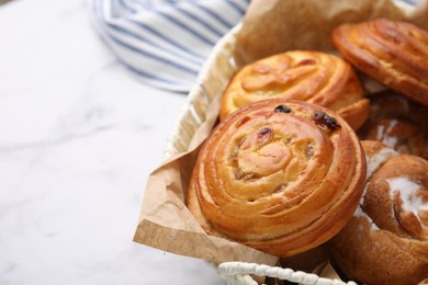 Photo of Delicious rolls with raisins and sugar powder on white marble table, closeup and space for text. Sweet buns