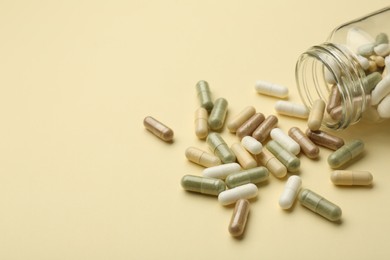 Photo of Vitamin pills and bottle on beige background, closeup. Space for text