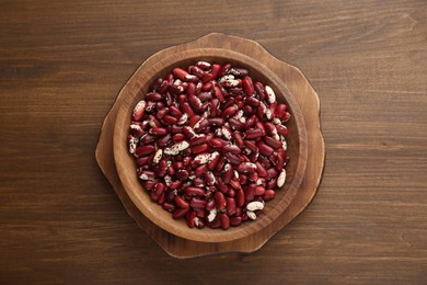 Photo of Bowl with dry kidney beans on wooden table, top view