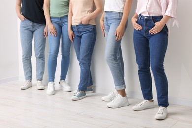 Photo of Women in stylish jeans near white wall, closeup