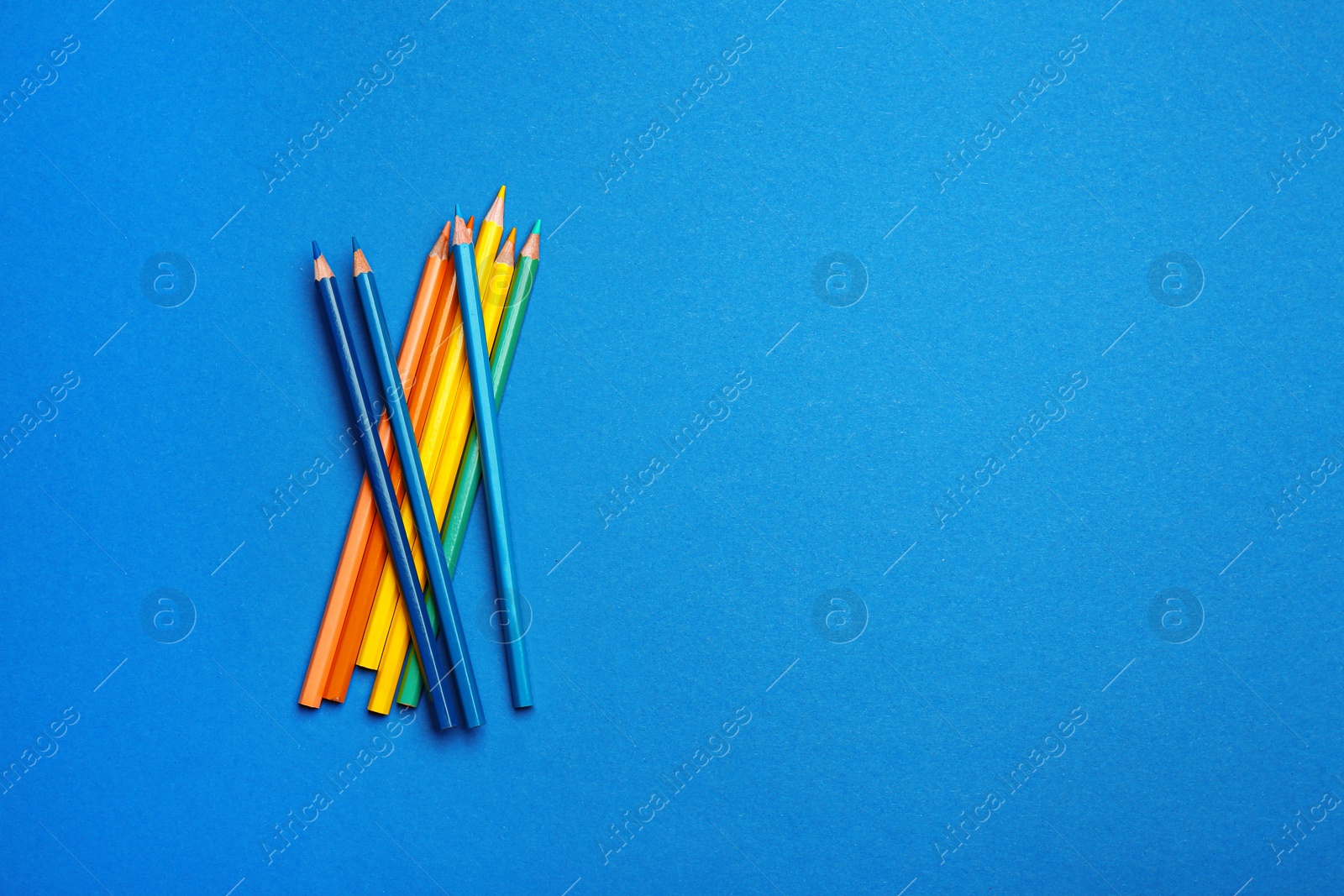 Photo of Color pencils on blue background, flat lay. Space for text