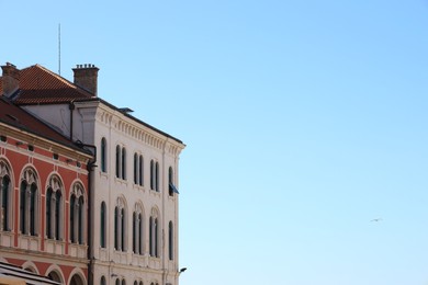 Photo of Exterior of buildings with arched windows against blue sky. Space for text