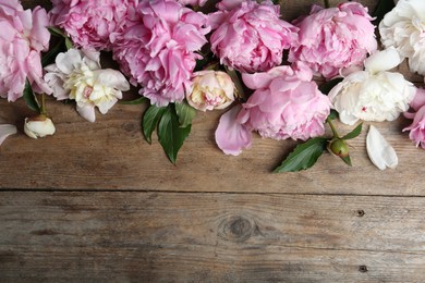 Beautiful peonies on wooden table, flat lay. Space for text