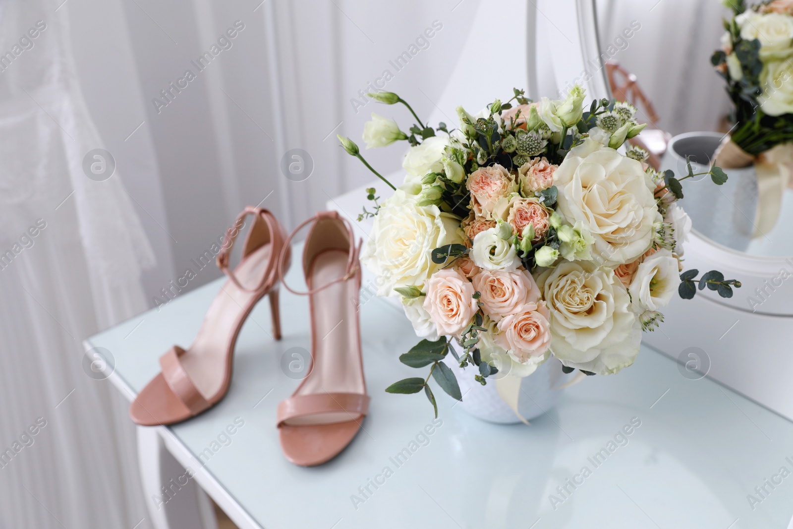 Photo of Beautiful wedding bouquet and shoes on dressing table indoors