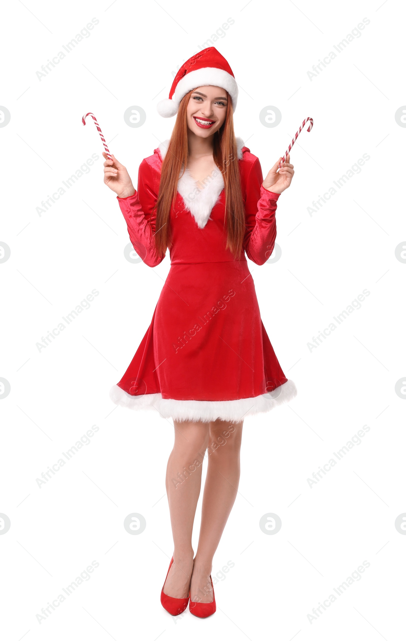 Photo of Young woman in red dress and Santa hat with candy canes on white background. Christmas celebration