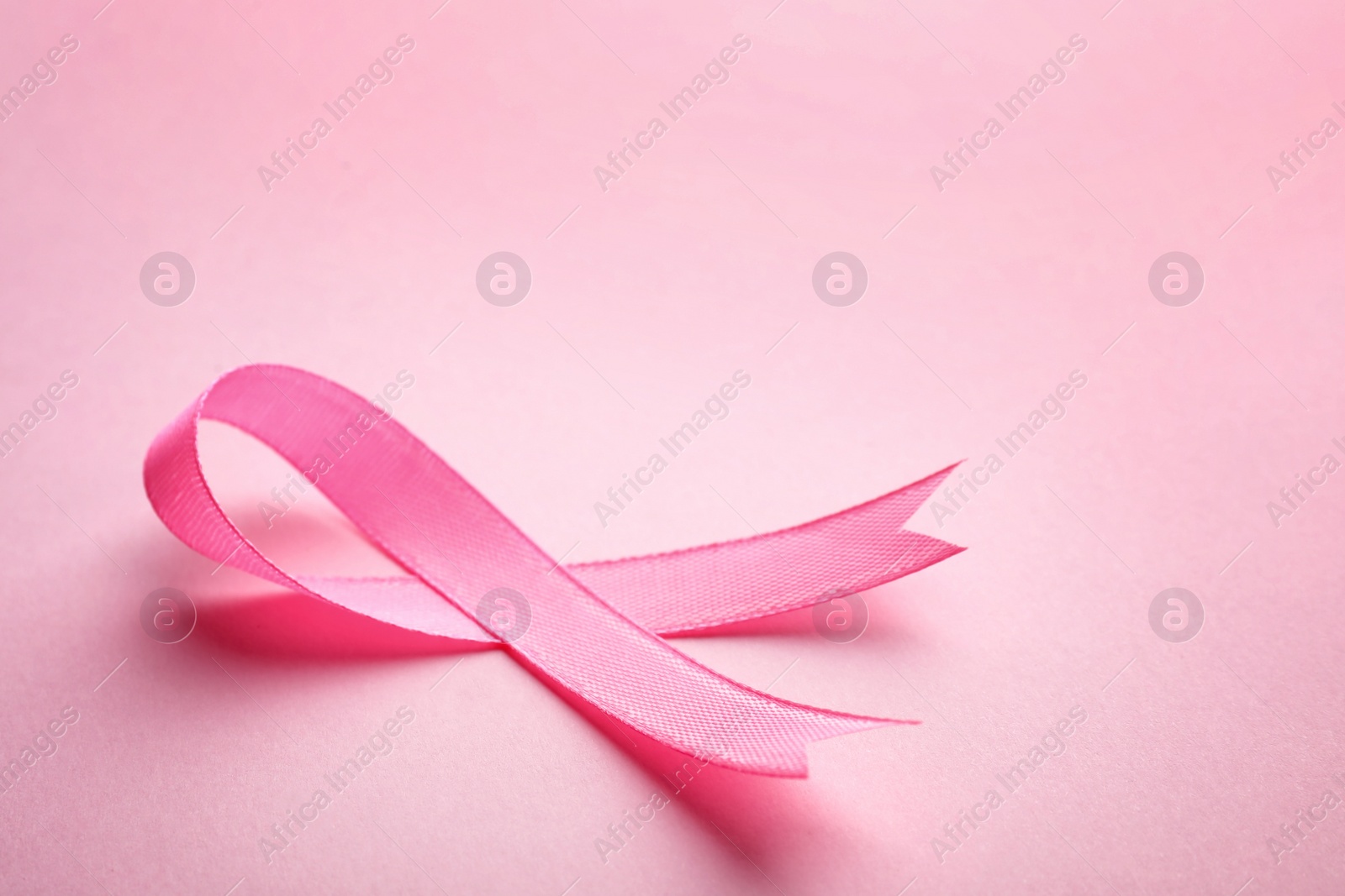 Photo of Pink ribbon on color background, space for text. Breast cancer awareness concept