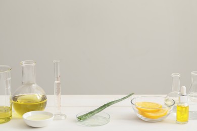 Developing cosmetic oil. Petri dish with aloe and laboratory dishware on white table, space for text