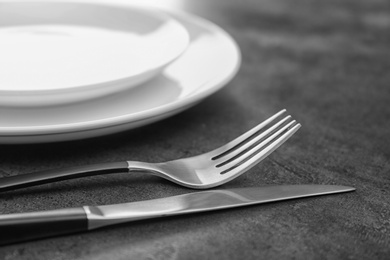 Photo of Empty dishware and cutlery on gray background, close up view. Table setting