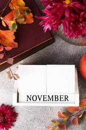 Photo of Thanksgiving day, holiday celebrated every fourth Thursday in November. Flat lay composition with wooden block calendar and autumn leaves on grey table