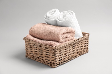 Photo of Basket with soft bath towels on grey background