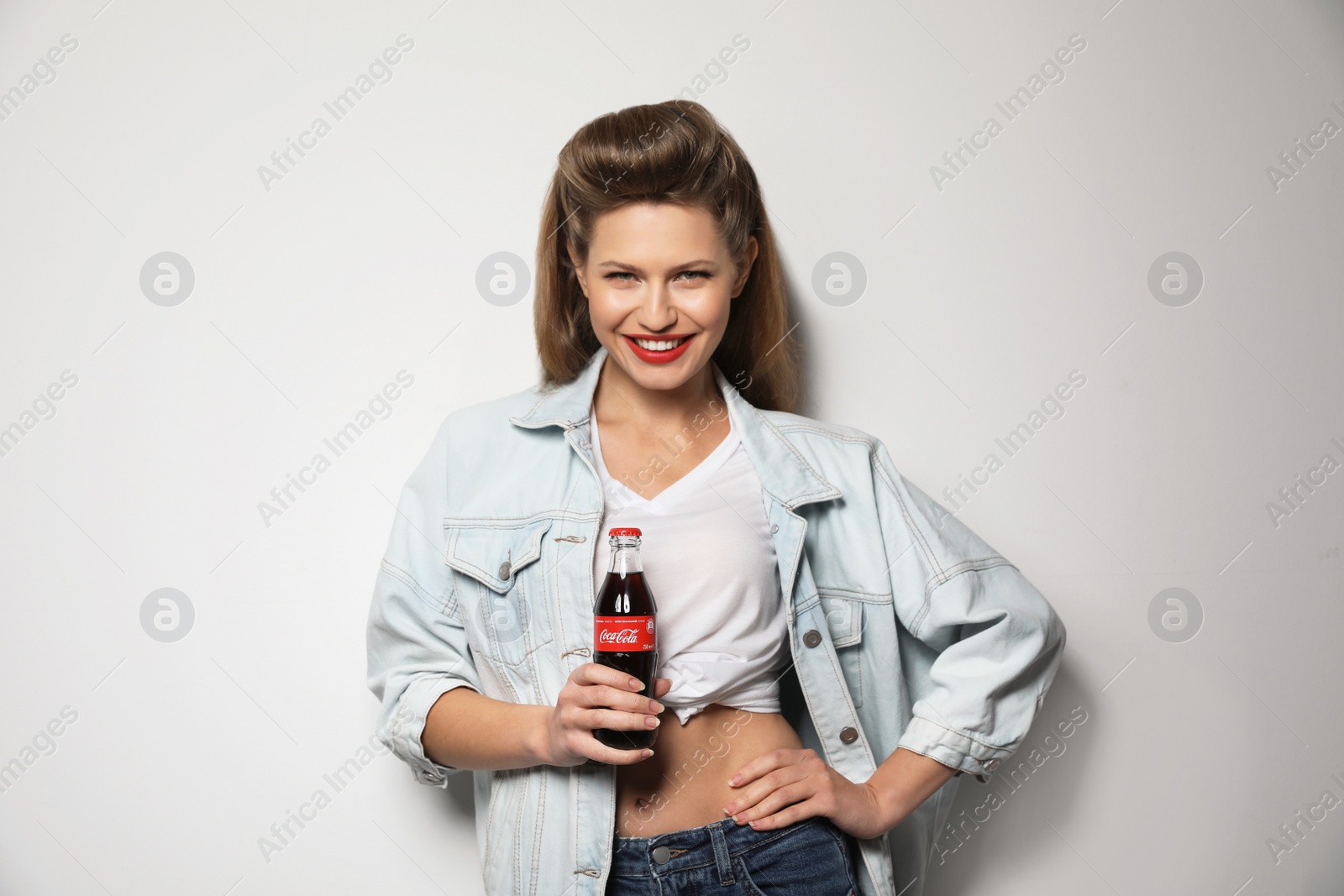 Photo of MYKOLAIV, UKRAINE - NOVEMBER 28, 2018: Young woman with bottle of Coca-Cola on white background