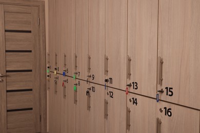 Photo of Many numbered wooden lockers with keys indoors
