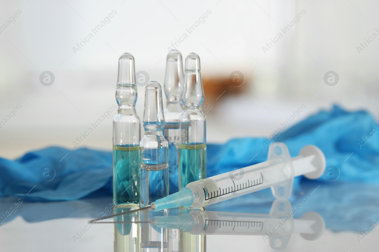 Photo of Glass ampoules, syringe and medical gloves on white table, closeup