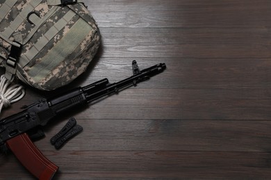 Flat lay composition with gun and military knapsack on wooden table. Space for text