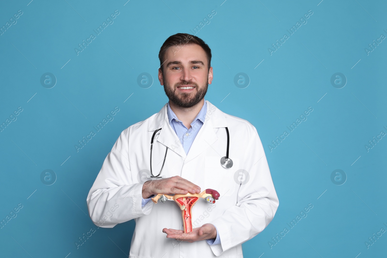Photo of Doctor demonstrating model of female reproductive system on light blue background. Gynecological care