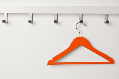 Photo of Rack with empty orange clothes hanger on white wall