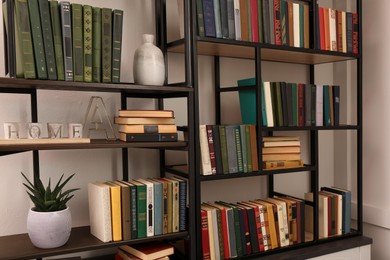 Photo of Collection of different books and decorative elements on shelves in home library