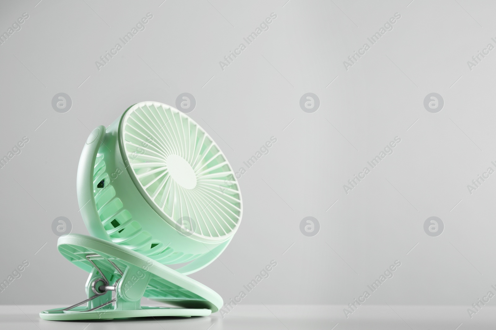 Photo of Portable fan on table against light grey background, space for text. Summer heat