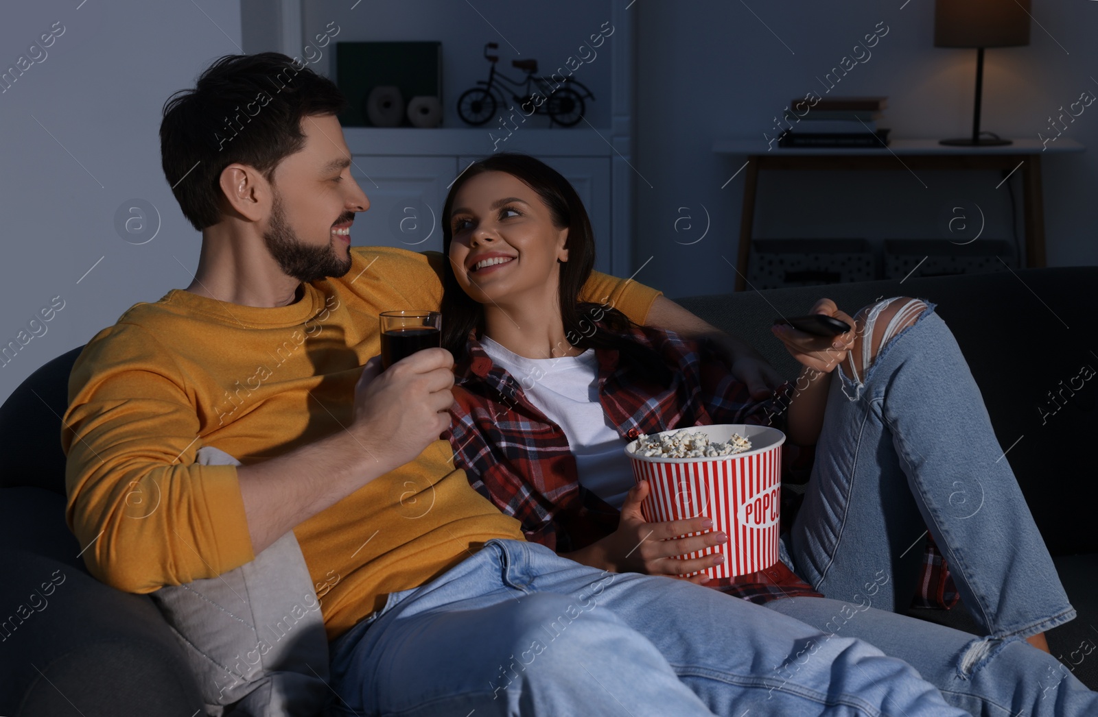 Photo of Happy couple spending time near TV at home in evening